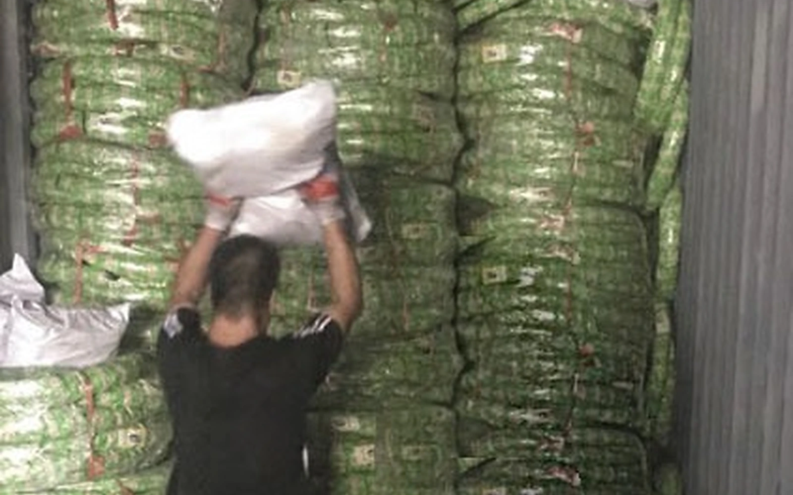 A worker manually loading wrapped motorcycle tyres into a container